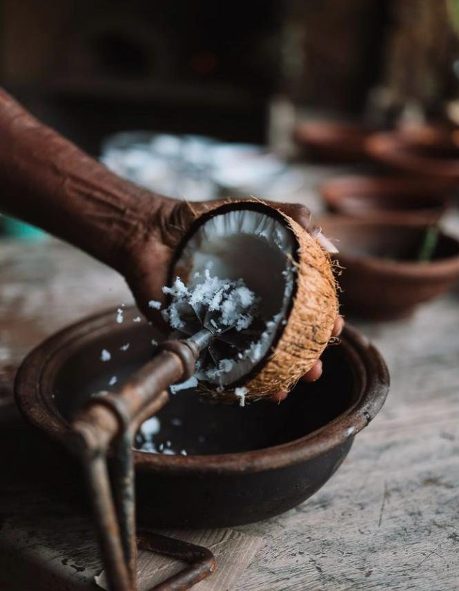 Scraping fresh coconut by hand for Hambu Café's live wood-fire cooking