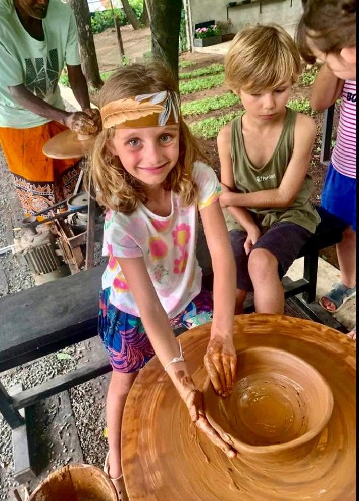 A young visitor shaping a bowl on the pottery wheel with a local potter at Hambu Café