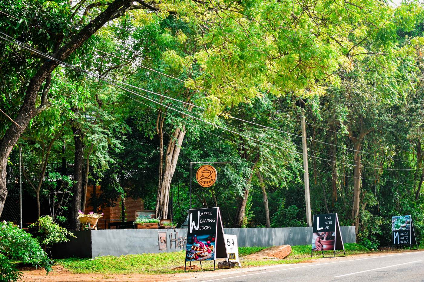 Hambu Café's roadside entrance in Girithale with hand-painted coffee signage and milepost marker
