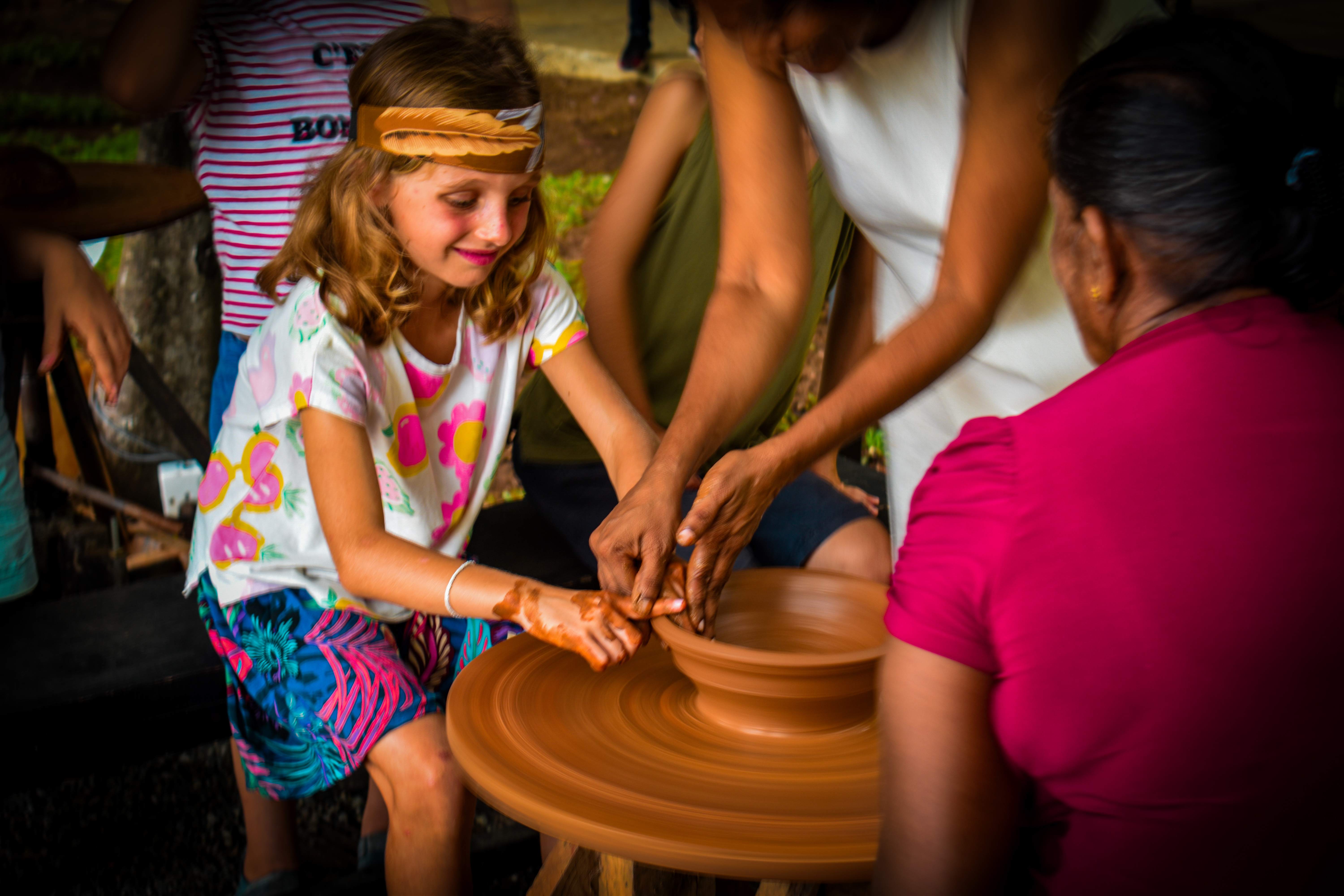 Child learning pottery techniques from local artisan